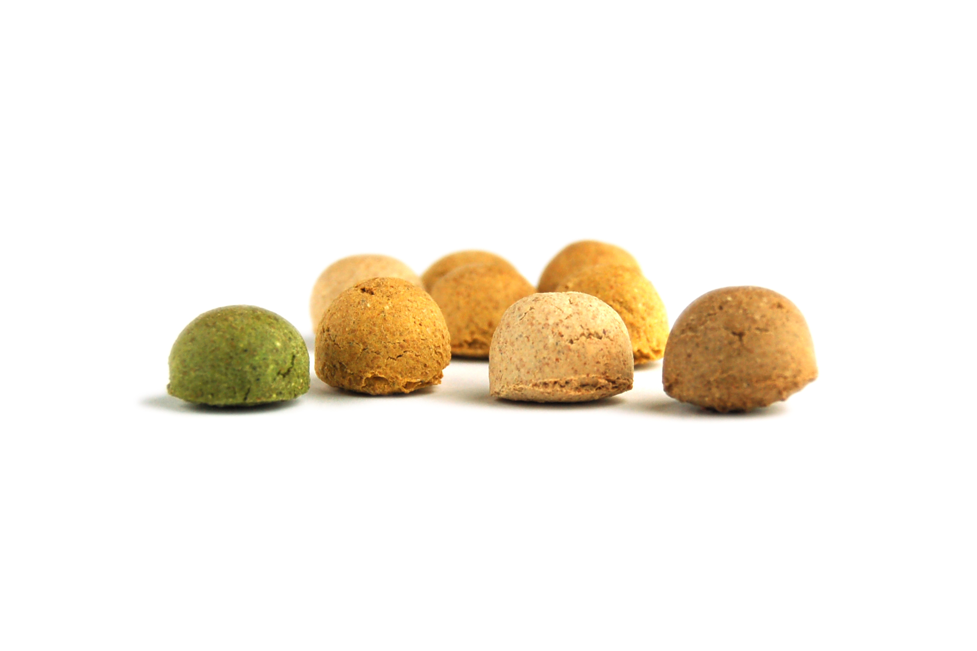Mehrfarbige Kugelform-Leckerlis für Hunde, grün, beige, orange, braun, auf weißem Hintergrund.