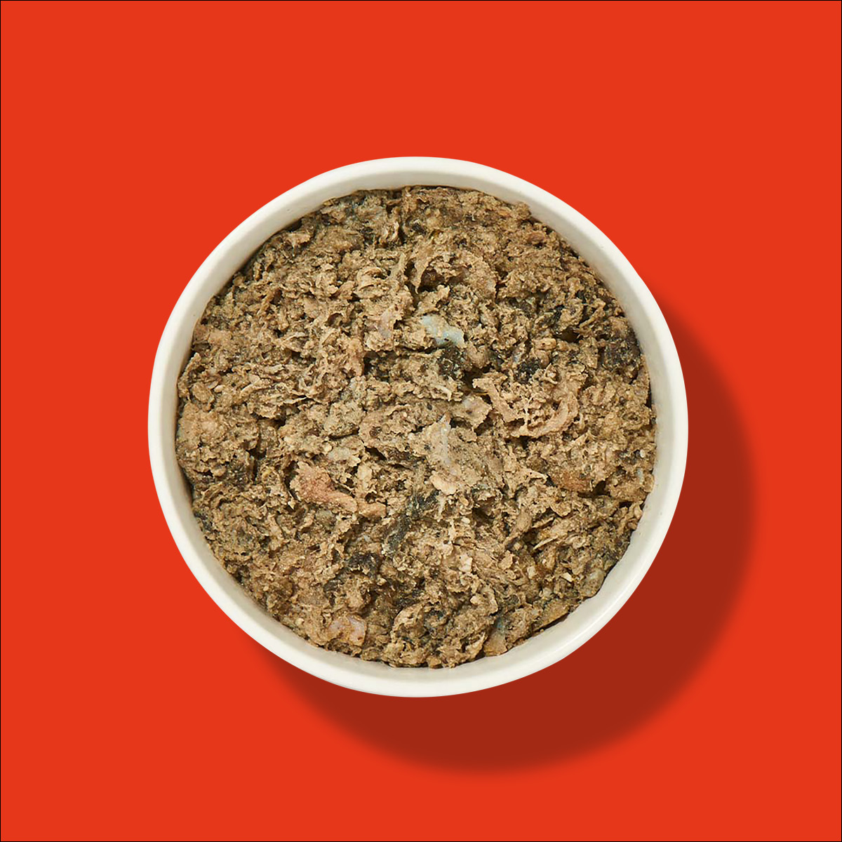 Nutriment Compact NATURPANSEN Weiße Schüssel mit Naturpansen vor rotem Hintergrund, Ansicht von oben
