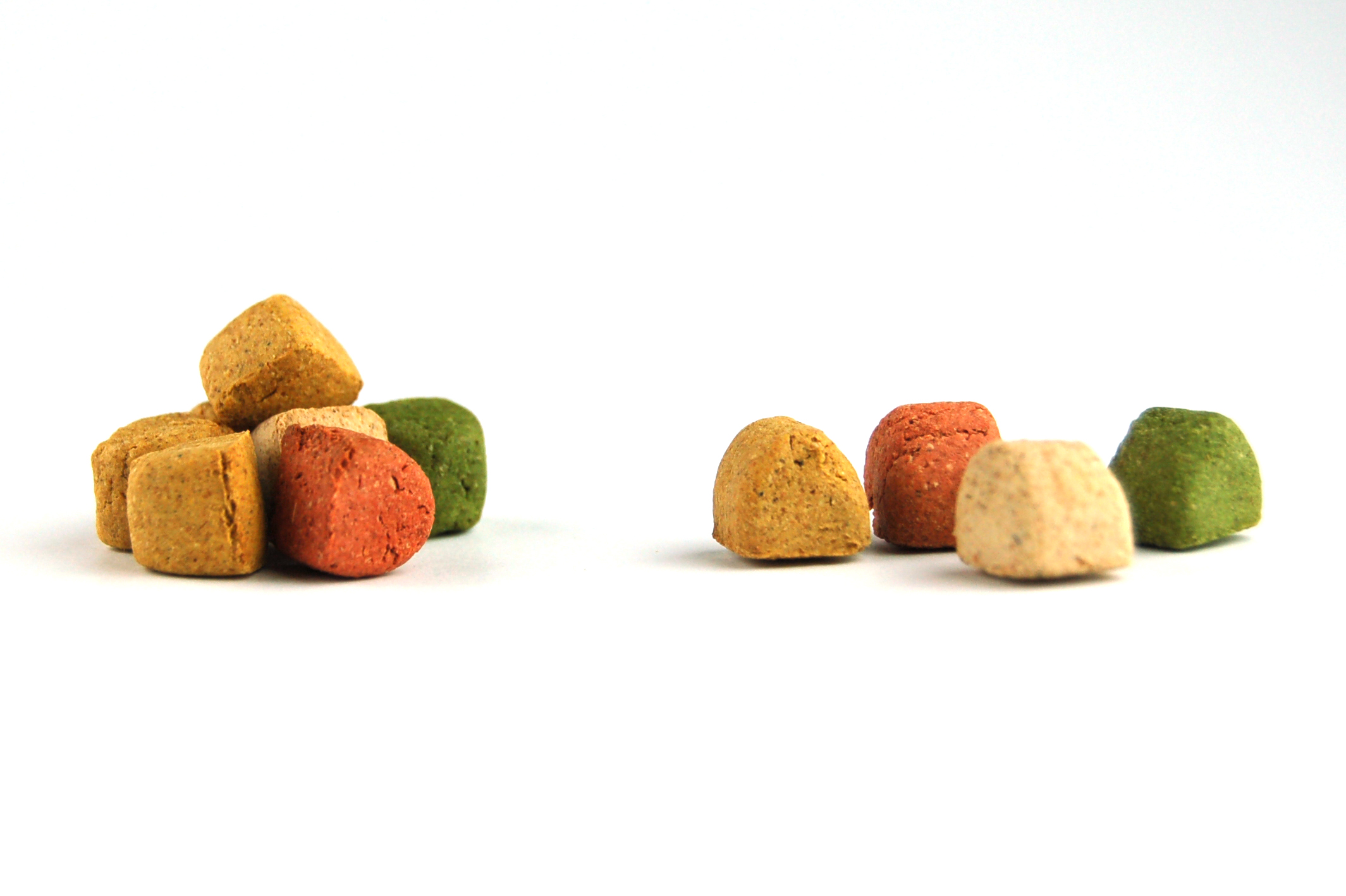 Tierfutter, gemischte Farben, runde Form, orange, grün, beige, zwei Haufen, helle Oberfläche.