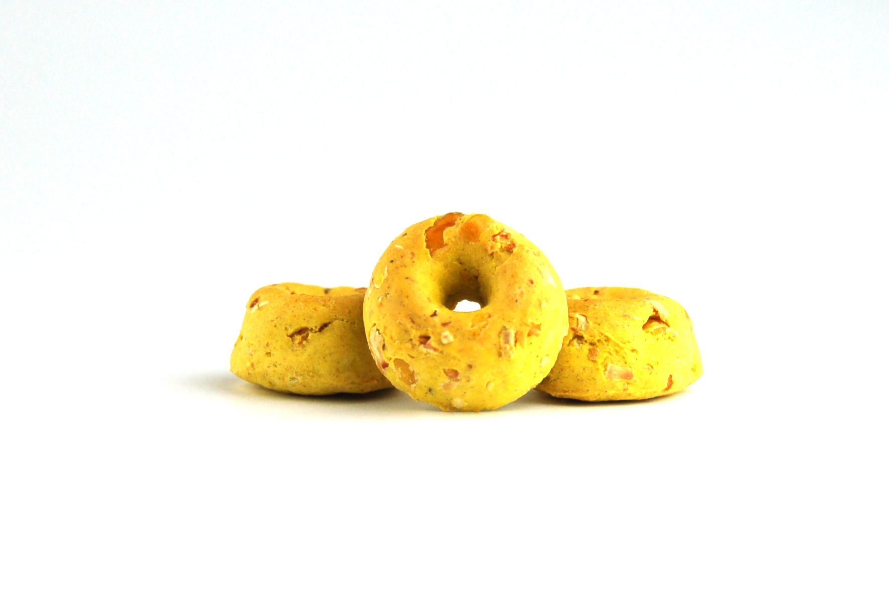 Donut-Kranz, gelb, kleine Stückchen, drei Stück, minimalistisch arrangiert.